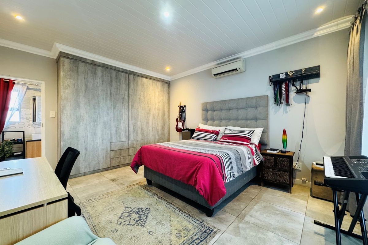 A well-maintained bedroom featuring built-in floor-to-ceiling cabinetry, tiled flooring, recessed ceiling lighting, and a wall-mounted air conditioning unit.