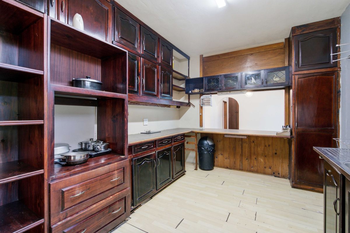 A dated kitchen featuring extensive dark wood cabinetry, a pass-through window to the adjacent room, and laminate flooring.