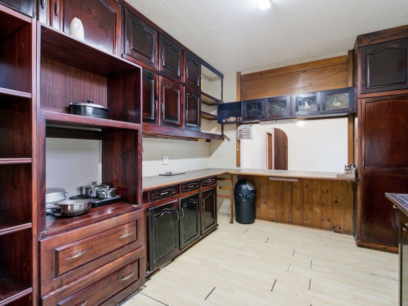 A dated kitchen featuring extensive dark wood cabinetry, a pass-through window to the adjacent room, and laminate flooring.