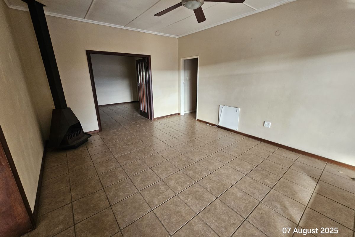 Spacious living area featuring tiled flooring, a built-in fireplace, and a ceiling fan, offering a neutral canvas for personalization.