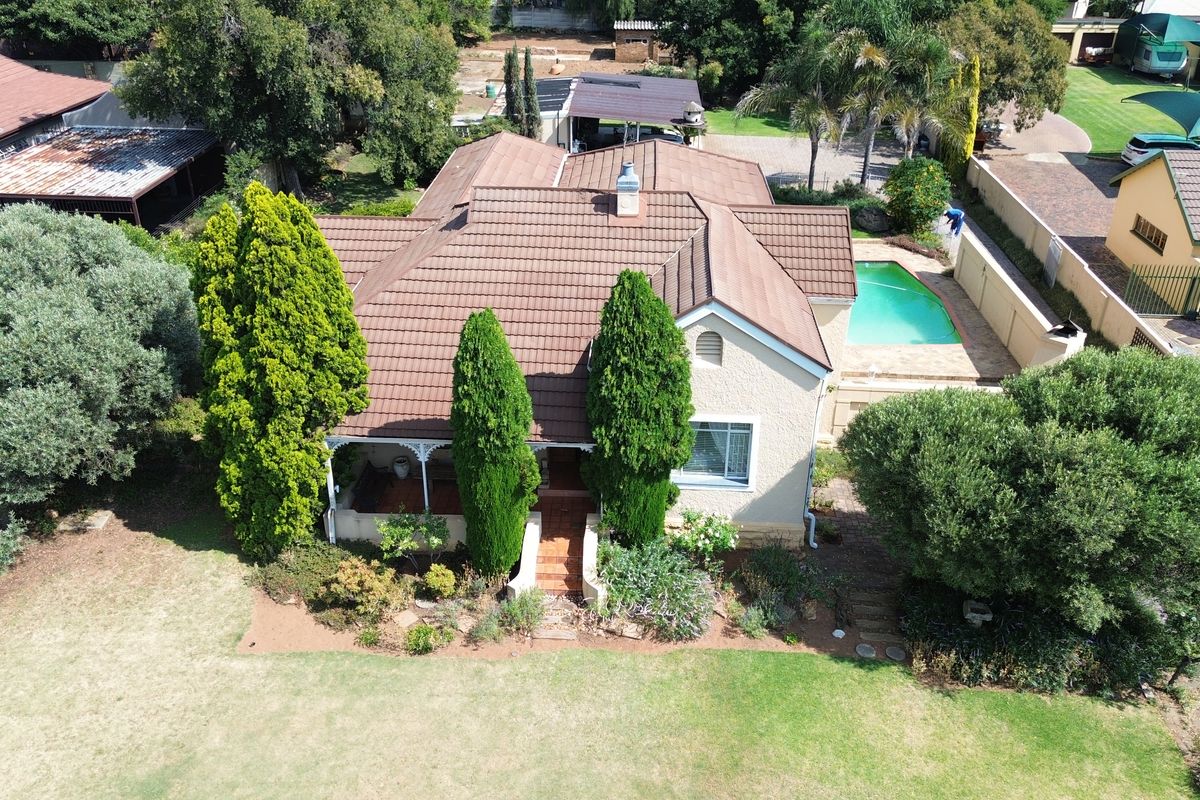 Aerial view of a residential property featuring a tiled roof house, a swimming pool, and established garden landscaping.