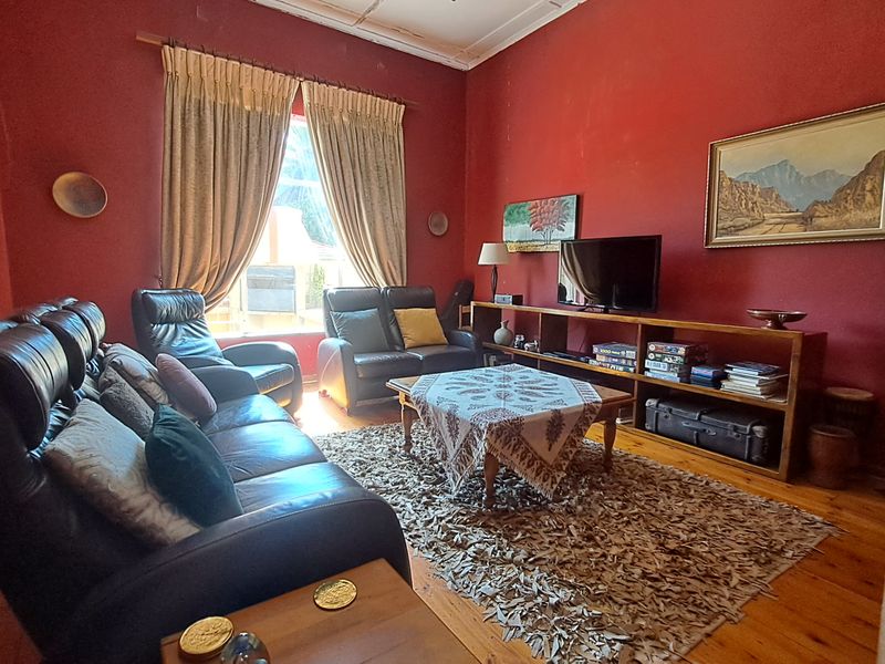 A living room featuring original timber flooring, high ceilings with decorative cornicing, and large windows allowing natural light.