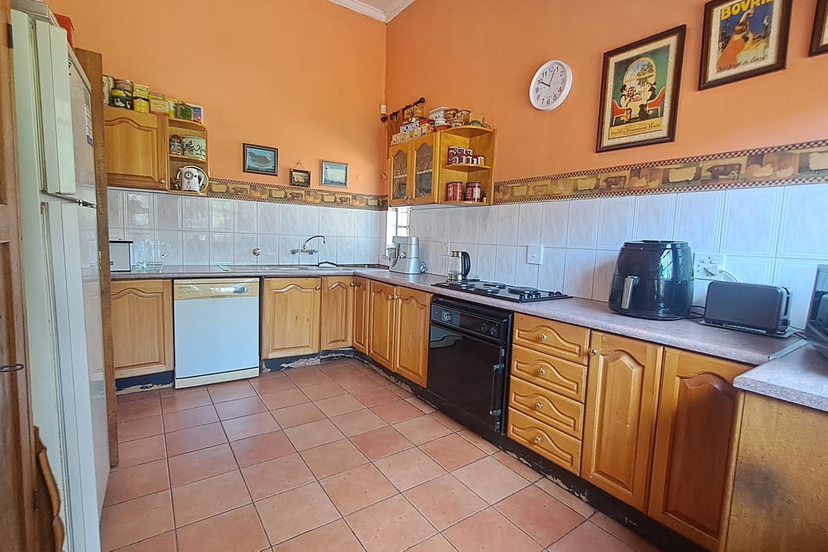 A functional kitchen featuring wooden cabinetry, tiled backsplash, and ceramic flooring, offering a traditional layout with built-in cooking appliances.