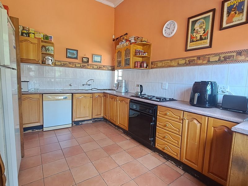 A functional kitchen featuring wooden cabinetry, tiled backsplash, and ceramic flooring, offering a traditional layout with built-in cooking appliances.