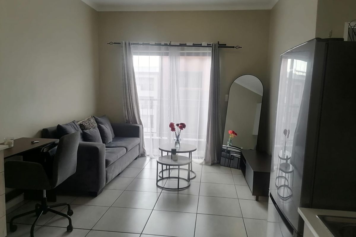 A compact living room featuring neutral tiled flooring and a sliding glass door that provides access to an outdoor area.