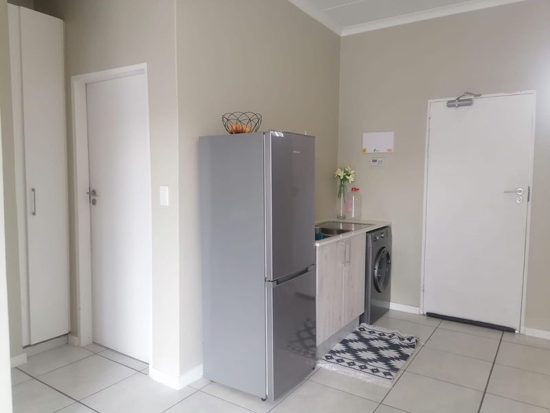 A functional laundry area featuring built-in cabinetry, a stainless steel sink, and tiled flooring, providing a practical space for household chores.