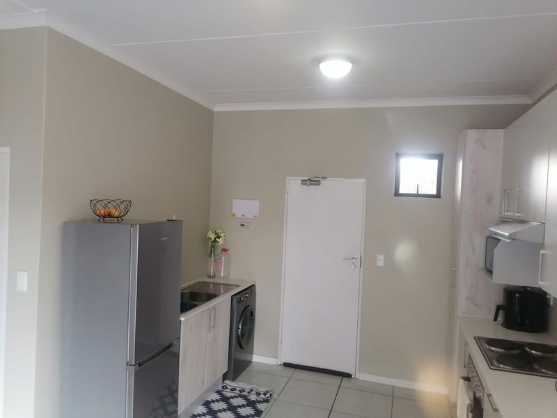 A functional kitchen featuring built-in cabinetry, a stainless steel sink, an electric hob with an extractor fan, and tiled flooring.