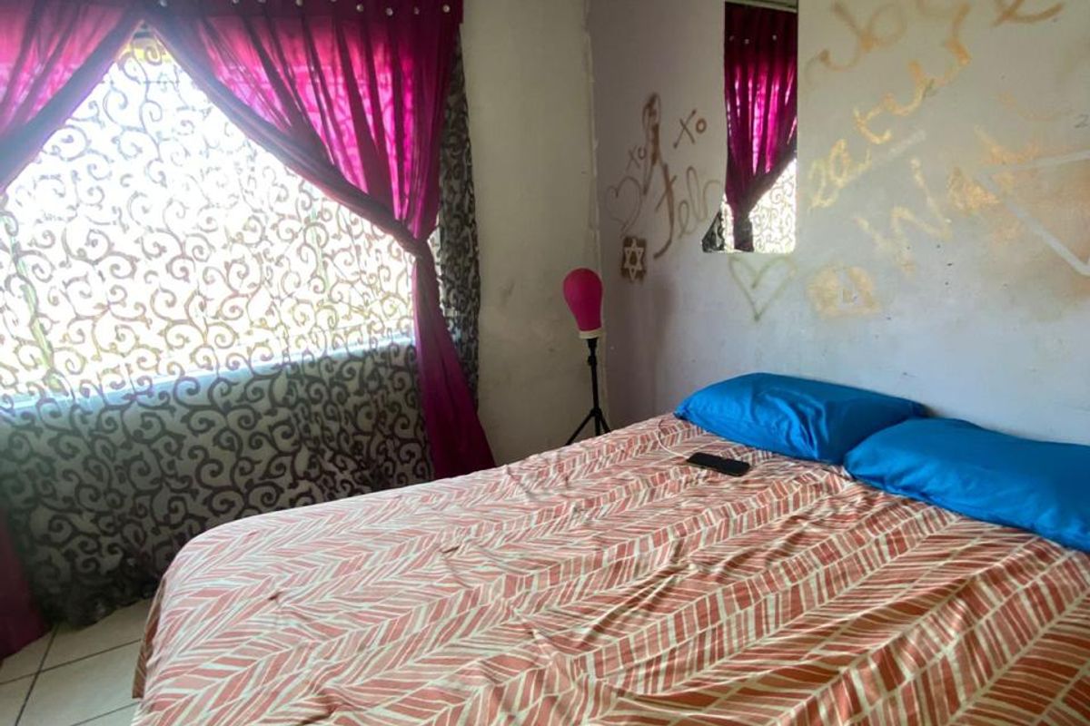 A bedroom featuring tiled flooring and significant wall damage, including graffiti and peeling paint, requiring cosmetic repairs and redecoration.
