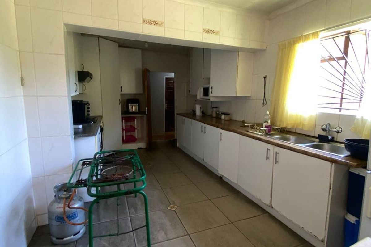 A functional kitchen featuring extensive built-in cabinetry, double basin sink, and tiled finishes, offering a practical layout ready for modernization.