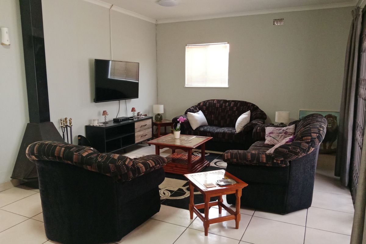 A comfortable living room featuring tiled flooring, a built-in fireplace, and a window with blinds, providing a functional and inviting space.
