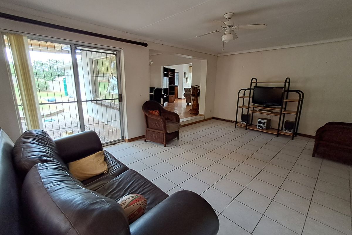 Spacious living room featuring tiled flooring, a ceiling fan, and large sliding glass doors providing access to the outdoor area.