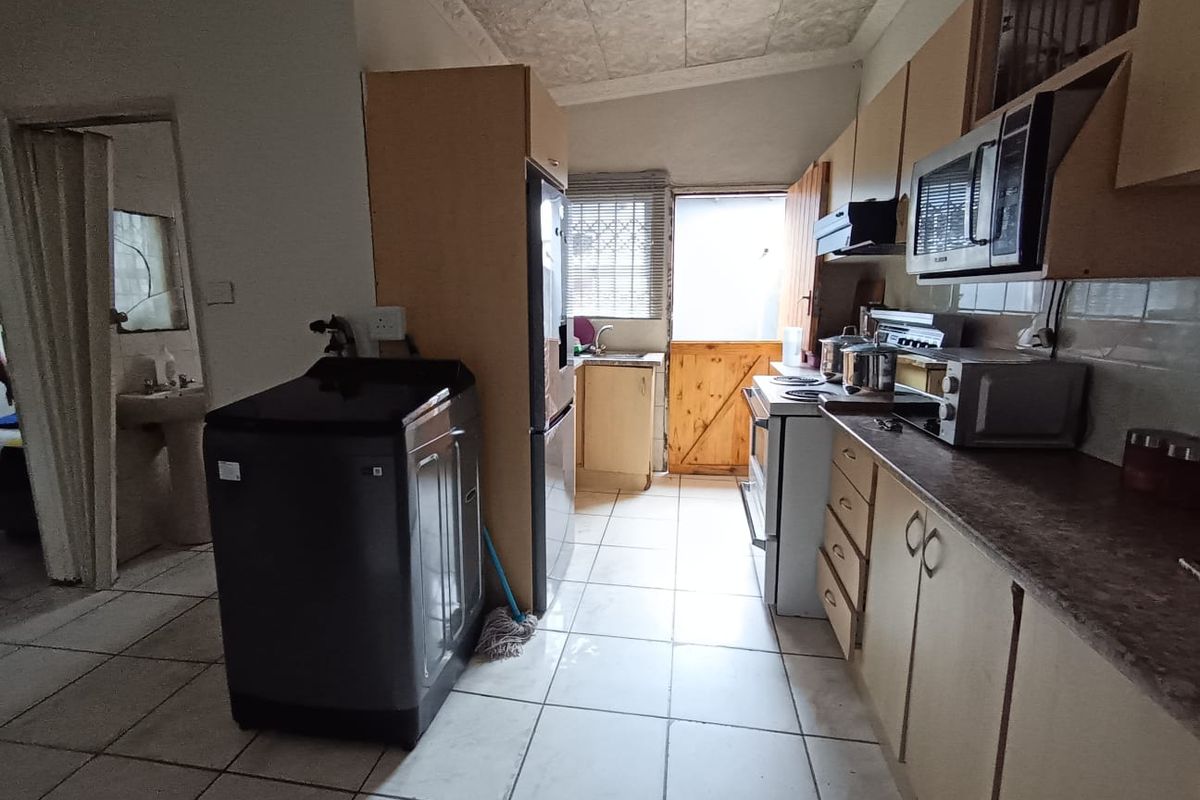 A functional kitchen featuring built-in cabinetry, laminate countertops, a freestanding stove, and direct access to an exterior stable door, with an adjacent laundry area.