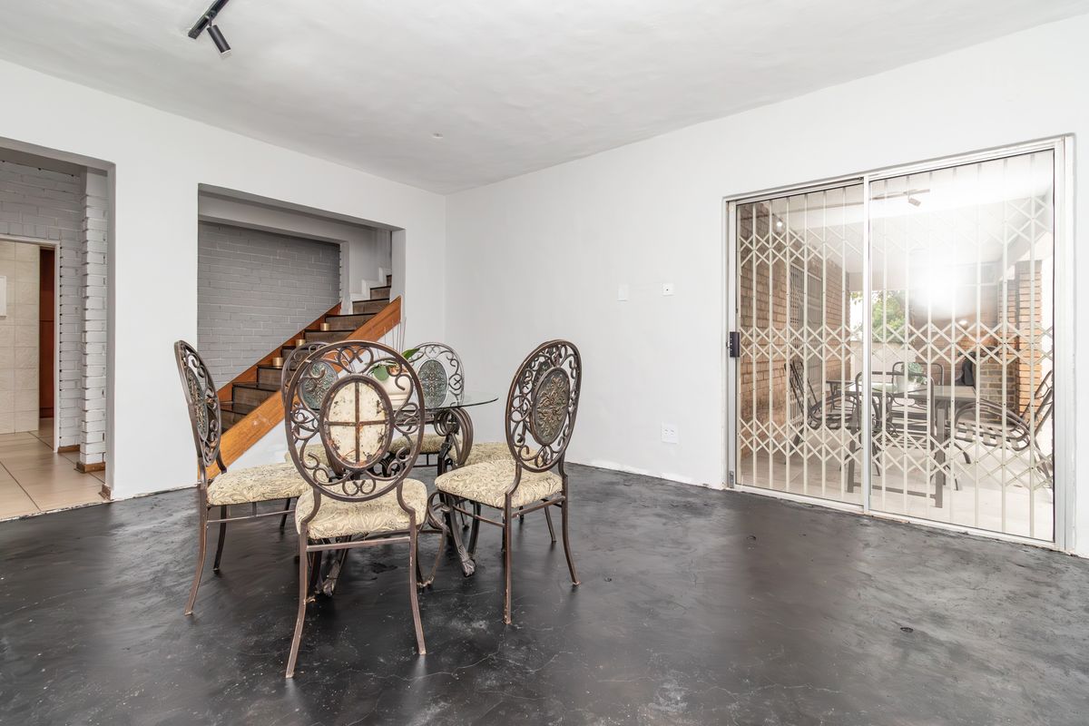 Open plan living area featuring a staircase, sliding glass doors with security gate, and dark painted flooring.