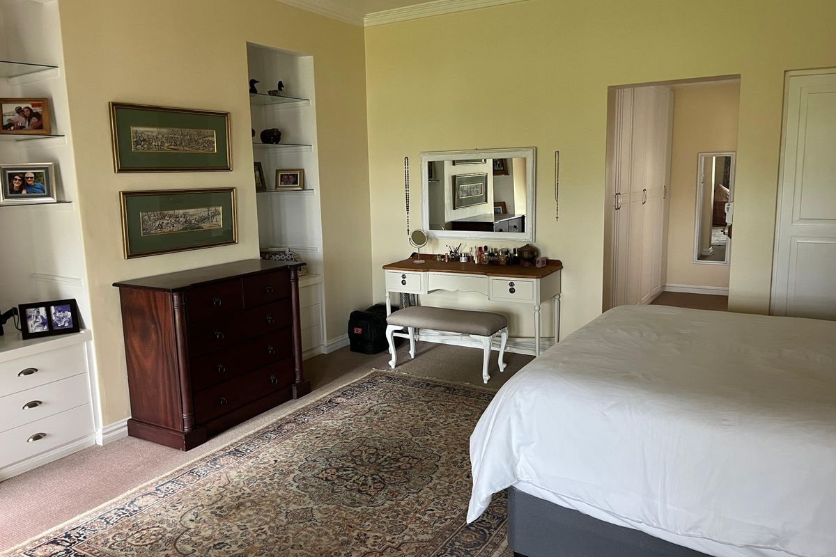 Spacious bedroom featuring built-in shelving units, recessed lighting, and an adjoining walk-in closet area with fitted cabinetry.