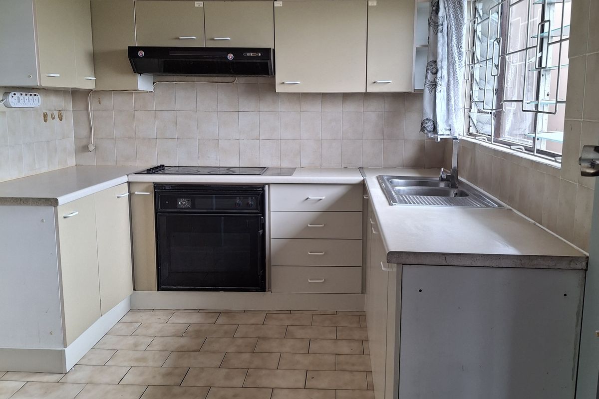 A functional kitchen featuring built-in cabinetry, an integrated oven and hob, and tiled finishes. The space is ready for a modern update.
