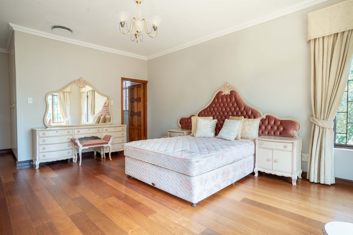 Spacious bedroom featuring polished hardwood flooring, neutral wall tones, and classic architectural cornicing, providing a comfortable and well-maintained living space.