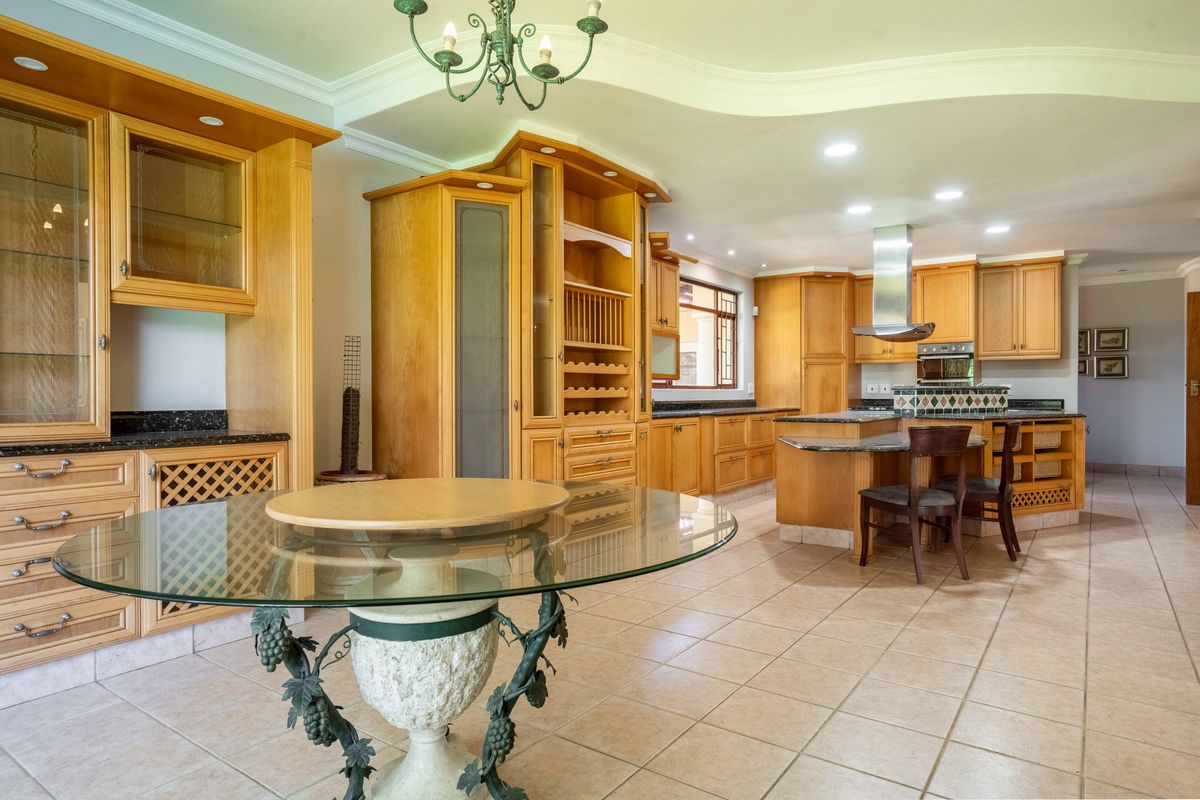 Spacious kitchen featuring extensive wooden cabinetry, granite countertops, built-in appliances, and tiled flooring, offering a functional layout with ample storage and preparation space.