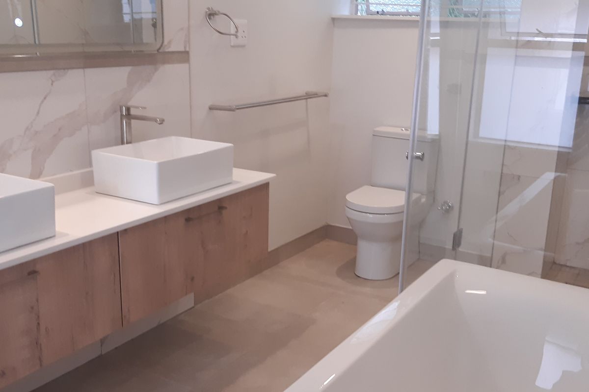 Modern bathroom featuring a double floating vanity with vessel sinks, a freestanding bathtub, and a glass-enclosed shower with a contemporary shower panel.