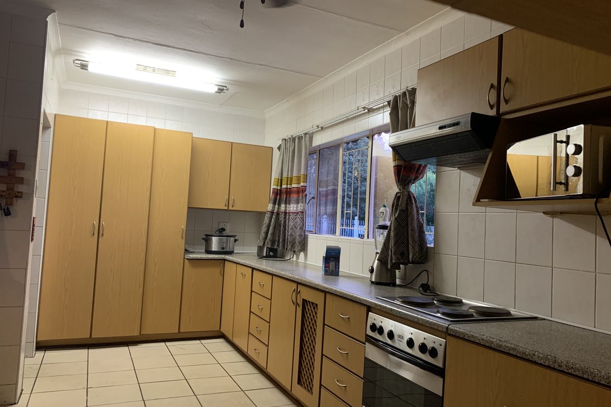 A functional kitchen featuring laminate cabinetry, tiled backsplash, and built-in cooking appliances, offering a practical layout with potential for modern updates.