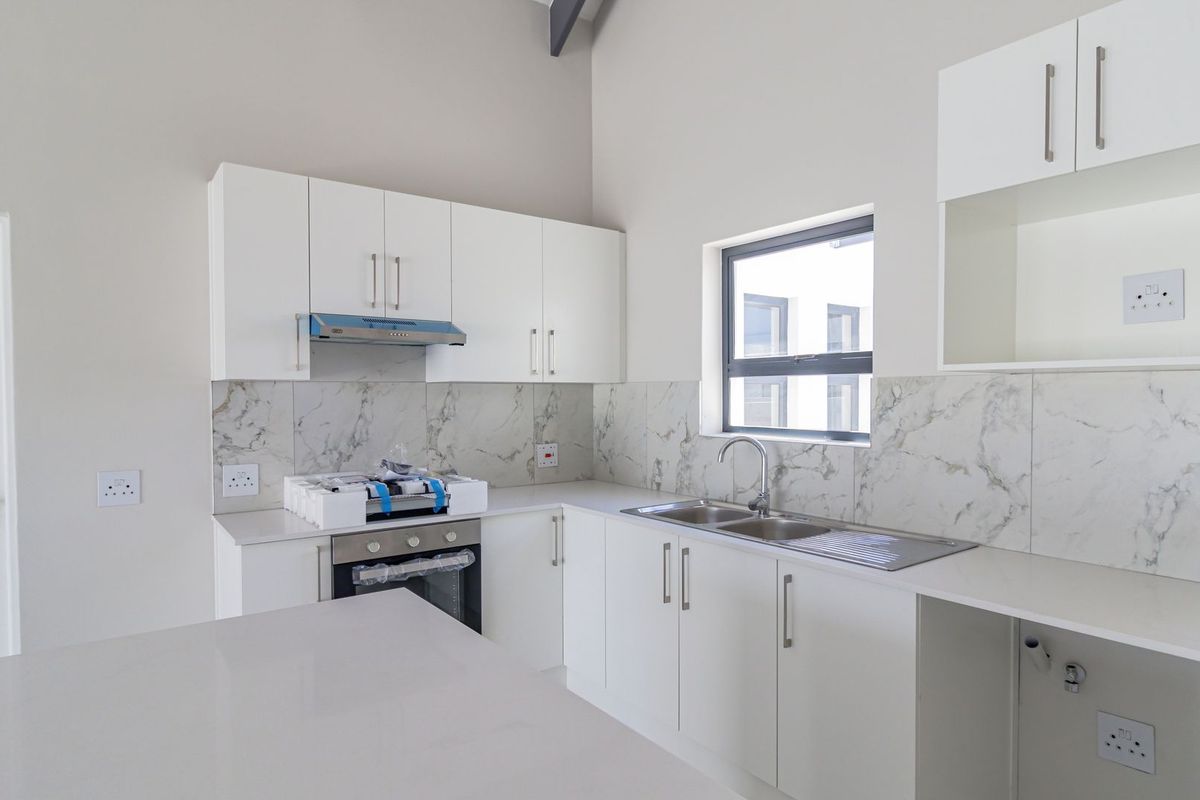 Modern kitchen featuring white cabinetry, quartz countertops, marble-look splashback, built-in oven, extractor fan, and a stainless steel sink.