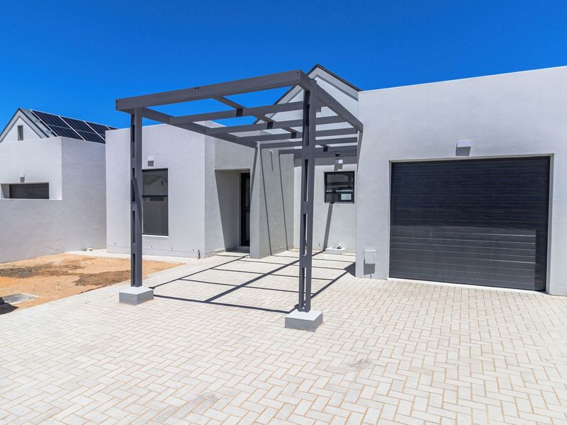 Modern front facade featuring a paved driveway, a structural pergola, and a single garage with a dark sectional door.