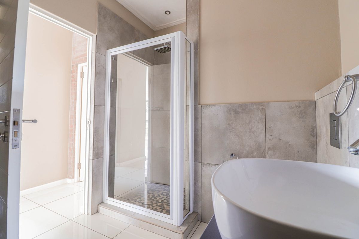 Modern bathroom featuring a glass-enclosed shower, large format wall tiles, and a contemporary vessel sink.