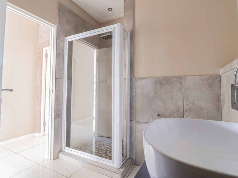 Modern bathroom featuring a glass-enclosed shower, large format wall tiles, and a contemporary vessel sink.