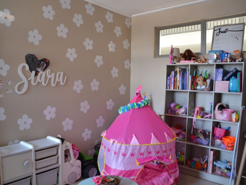A bedroom featuring a high-level clerestory window and decorative wall finishes, currently utilized as a children's play area.