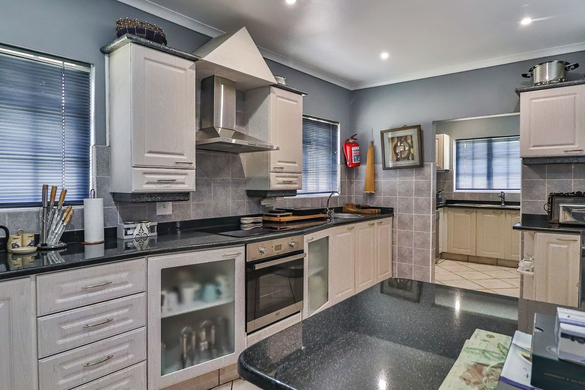 A well-appointed kitchen featuring granite countertops, built-in oven, extractor fan, and ample cabinetry, with an adjacent scullery area visible.