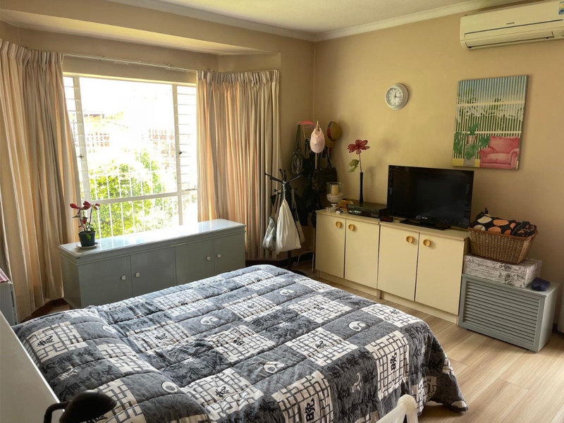 A bedroom featuring laminate flooring, a split-system air conditioner, and built-in storage cabinetry with a large window providing natural light.