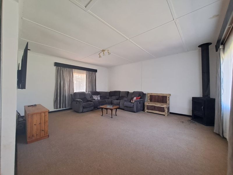 Spacious living room featuring a built-in wood-burning fireplace, neutral wall finishes, and carpeted flooring, offering a comfortable and functional family living space.