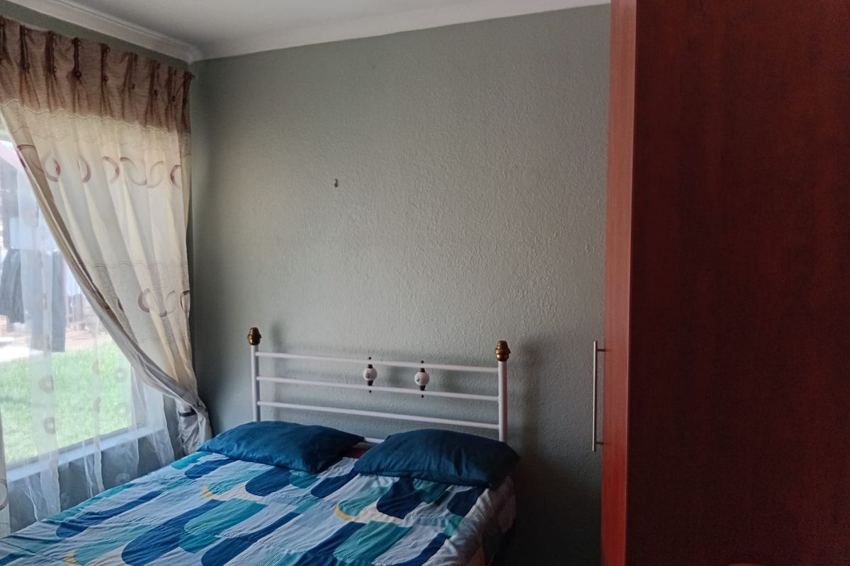 A functional bedroom featuring a built-in wardrobe and natural light from the window.