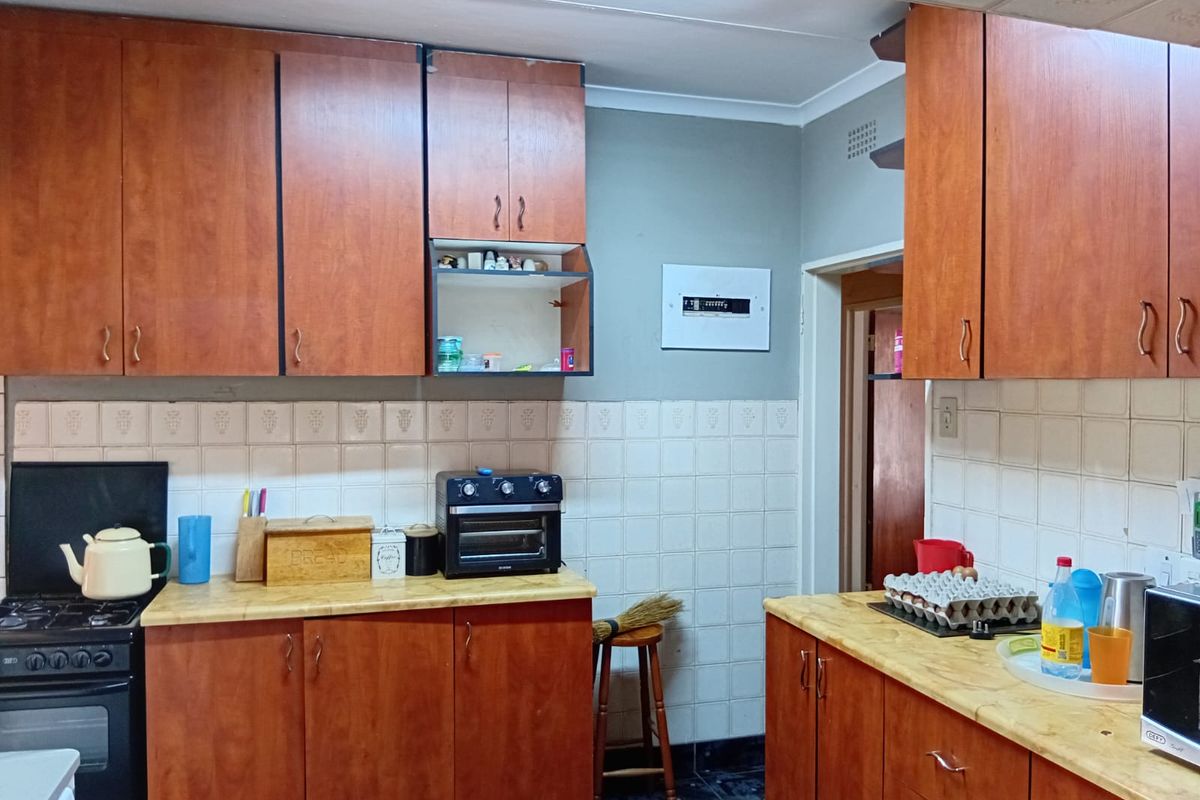 Functional kitchen featuring wood-look cabinetry, tiled backsplash, and integrated stove, offering a practical layout for daily meal preparation.