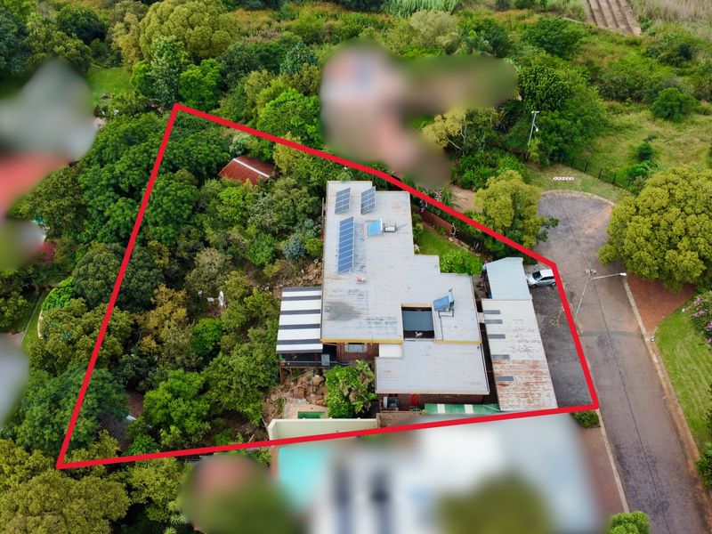 Aerial view of the property showing the roof structure with solar panels, solar geyser, swimming pool, and surrounding garden area.