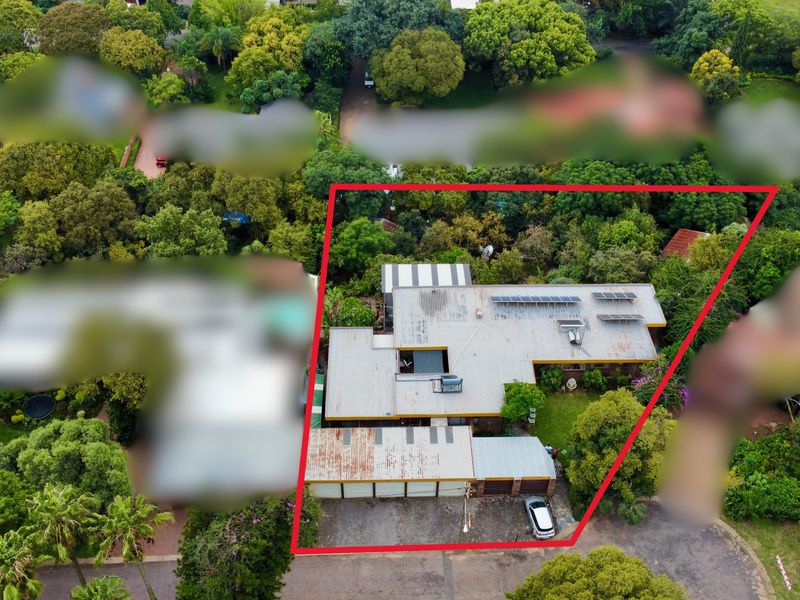 Aerial view of the property showing the roof structure, solar panels, driveway, and surrounding garden area within the highlighted boundary.