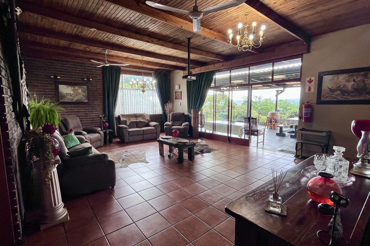 Spacious living room featuring exposed timber beam ceilings, tiled flooring, and large sliding glass doors opening to an outdoor patio area.