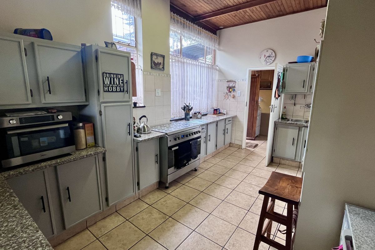 A functional kitchen featuring tiled flooring, built-in cabinetry, a freestanding oven, and a timber-paneled ceiling, offering a classic layout with ample storage space.