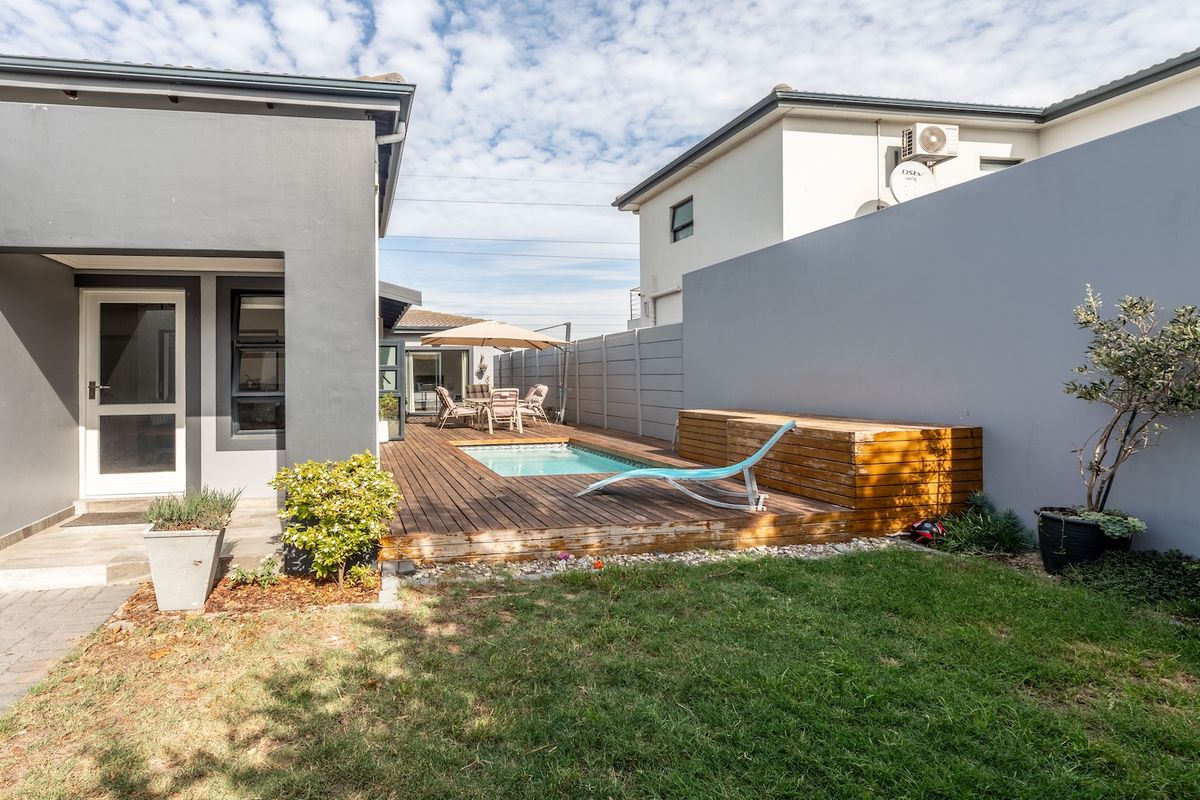 A private rear courtyard featuring a timber deck, a small plunge pool, and a low-maintenance garden area enclosed by high boundary walls.