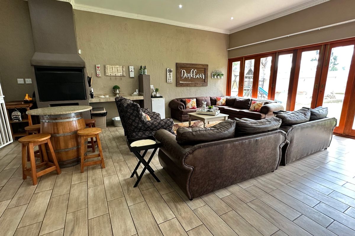 Spacious living area featuring a built-in braai, tiled flooring, and large wooden folding doors that provide seamless access to the outdoor space.