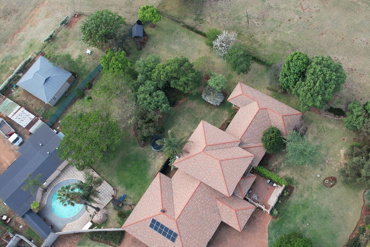 Aerial view of the small holding property featuring a main residence with solar panels, a swimming pool, and extensive landscaped garden areas.