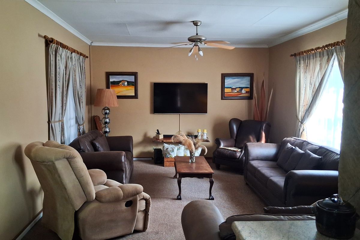 A comfortable living room featuring carpeted flooring and a central ceiling fan, providing a functional and inviting space for relaxation.