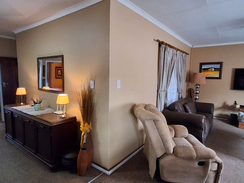 A living room area featuring neutral wall tones, carpeted flooring, and cove cornicing, providing a functional space with potential for modern updates.