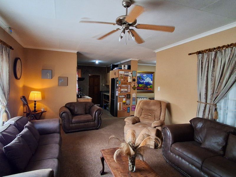 A spacious living room featuring a ceiling fan and large windows with curtain rods, providing a comfortable and functional living area.
