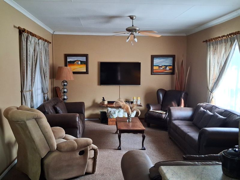 A comfortable living room featuring carpeted flooring and a central ceiling fan, providing a functional and inviting space for relaxation.