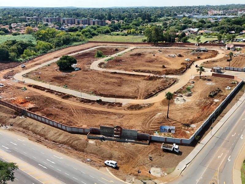 Aerial view of a residential development site featuring cleared land, internal road infrastructure, and perimeter walling in a suburban setting.