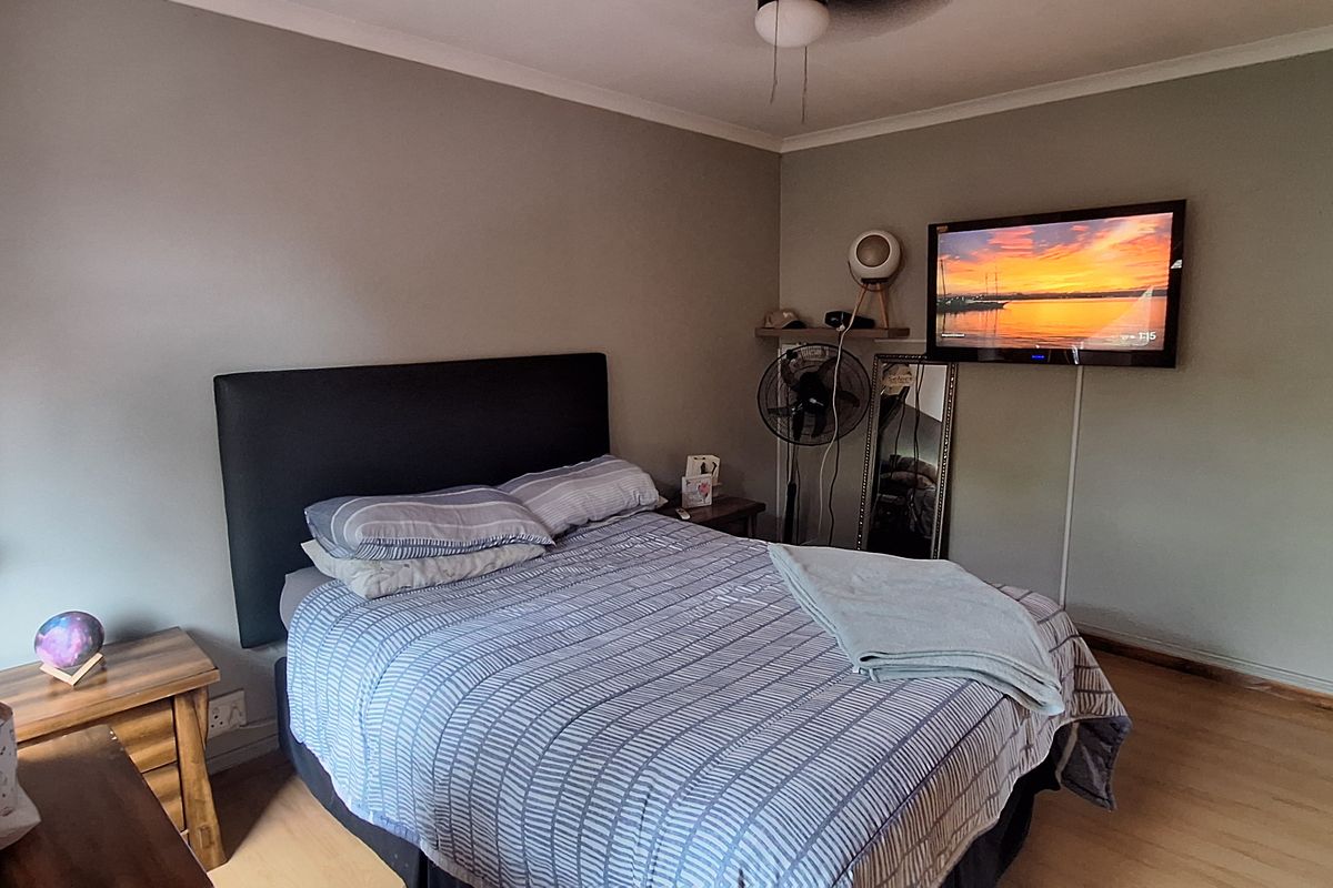 A functional bedroom featuring laminate flooring, a ceiling fan, and neutral wall tones, providing a comfortable and practical living space.