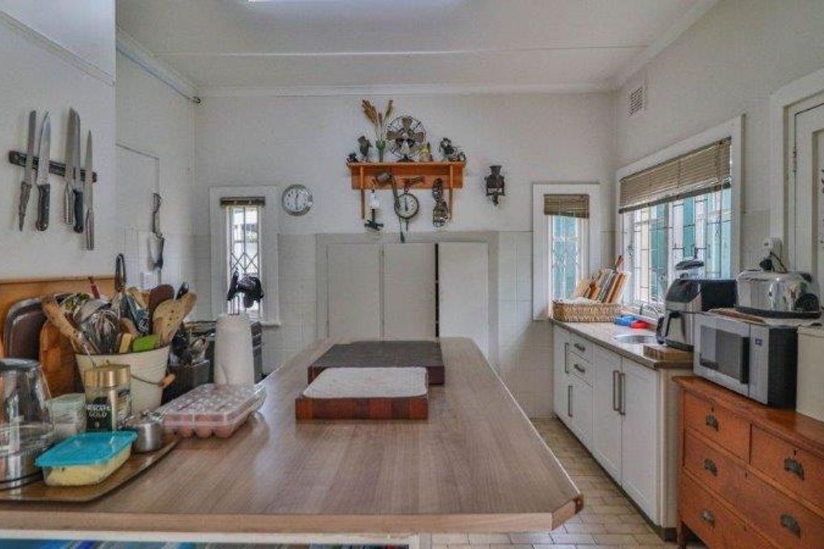 A functional kitchen featuring laminate countertops, ample cabinetry, and a central island workspace with tiled flooring and natural light.