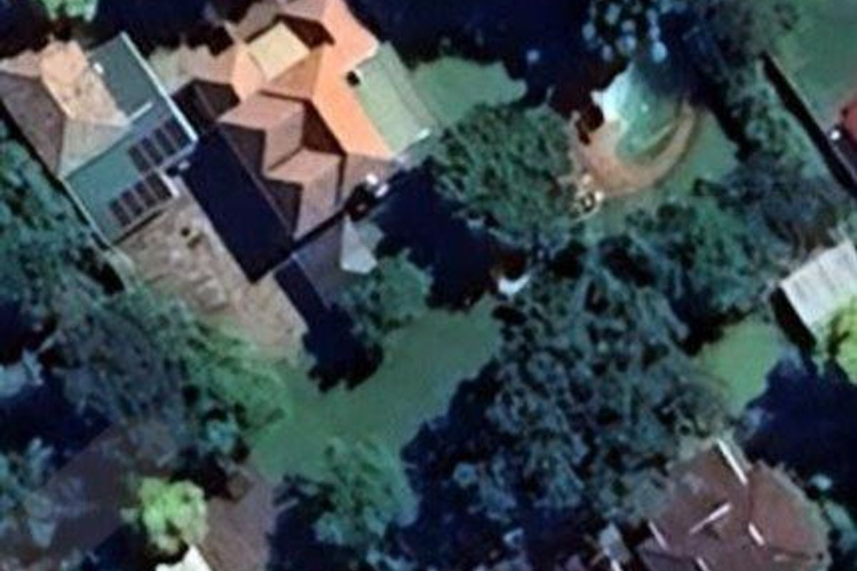 Aerial view of the property showing the main dwelling, surrounding garden, and swimming pool area.