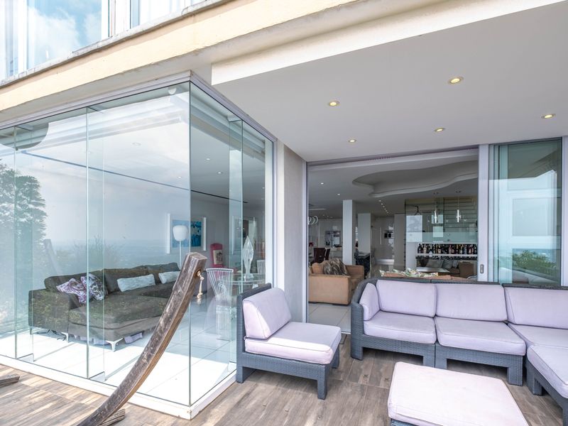 A spacious covered patio featuring glass-enclosed living areas, recessed lighting, and seamless indoor-outdoor flow, perfect for entertaining.