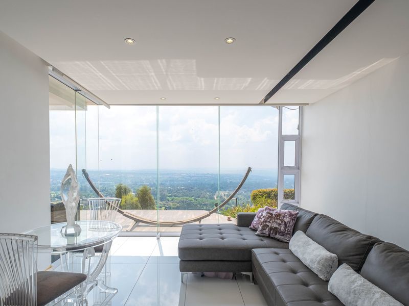 Modern open-plan living area featuring floor-to-ceiling glass walls that provide expansive panoramic views and seamless access to the outdoor balcony.